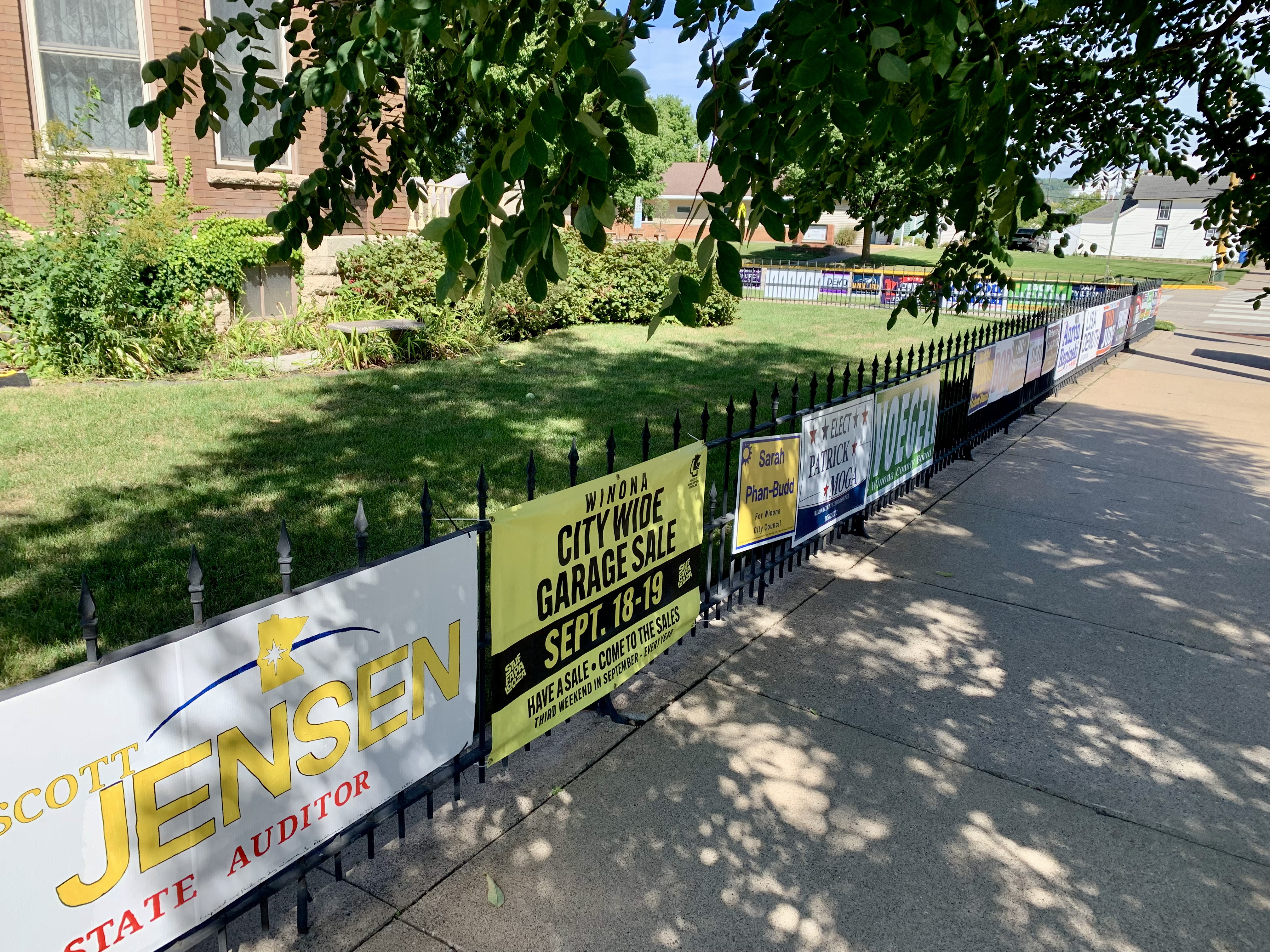 A fence lining a sidewalk has a
number of different campaign signs attached.
